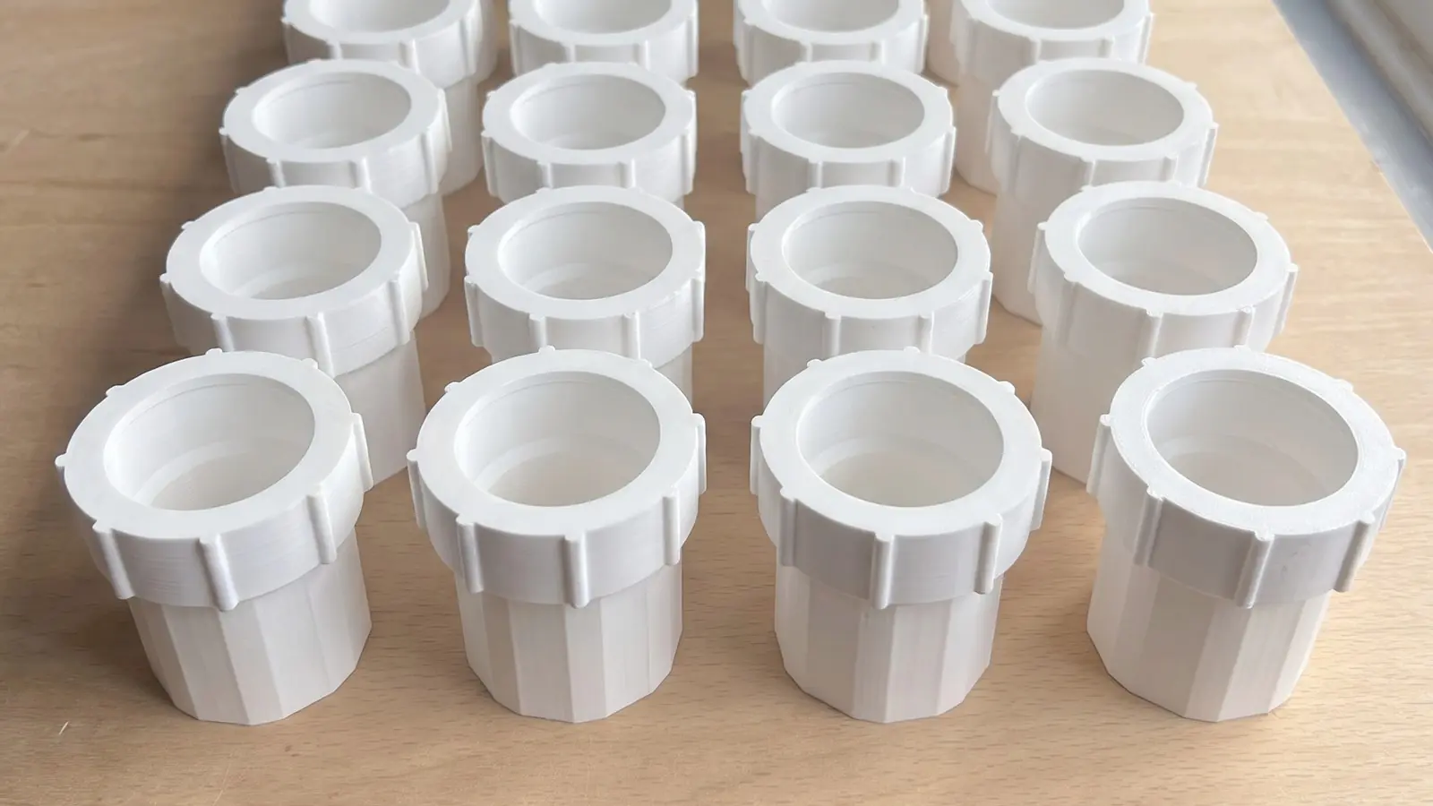 AI image made from photos of the real parts: rows of white 3D printed couplers with ribbed nuts fitted, lined up on a wooden workshop table