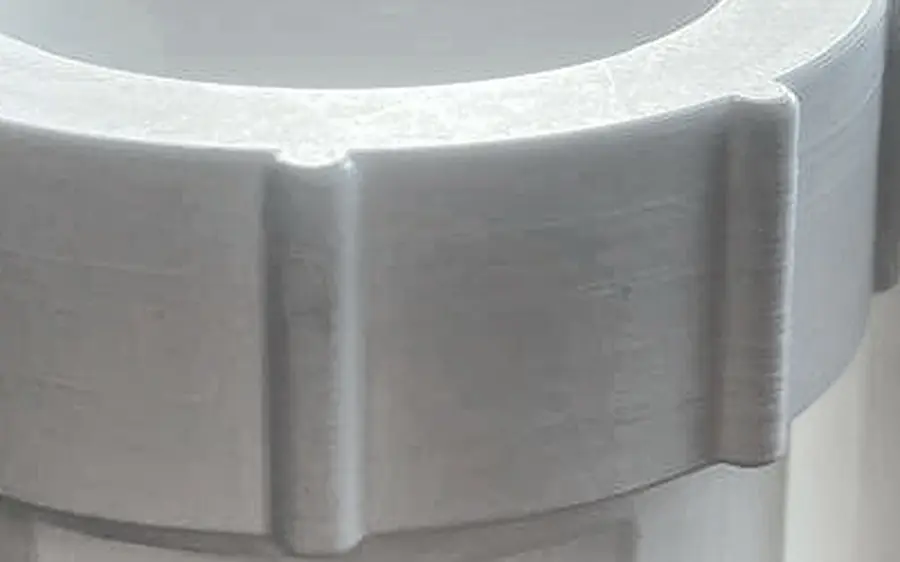 Close-up of a ribbed nut on a 3D printed coupler, with the printed layers visible on the nut ring