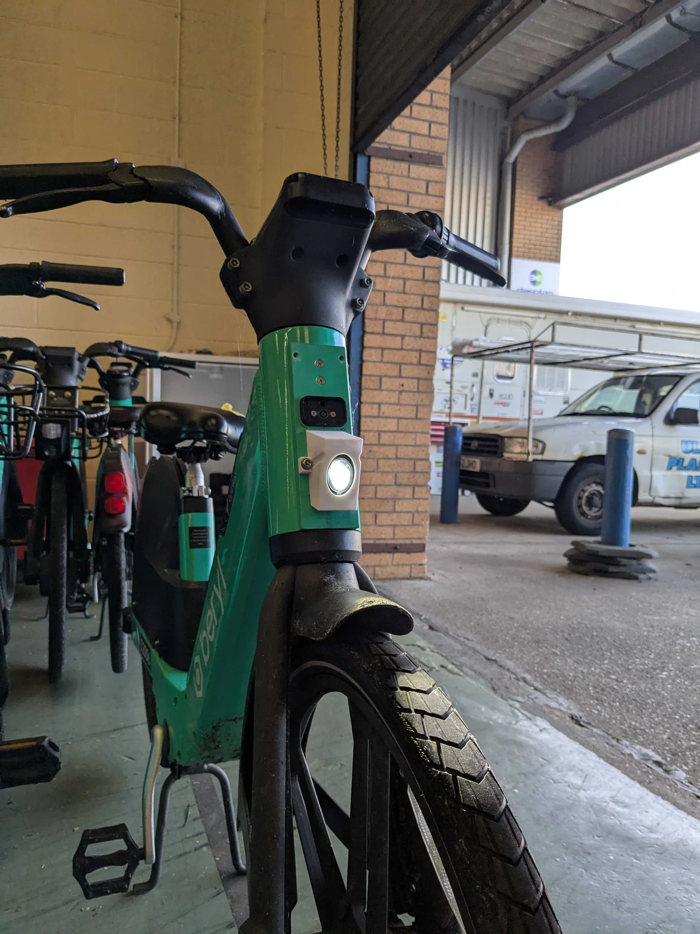 The 3D-printed light mount fitted to a Beryl e-bike with the rest of the fleet racked behind, at the depot