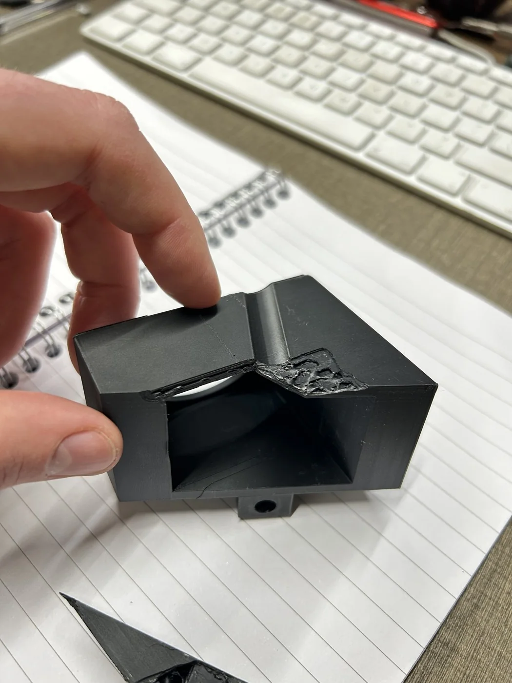 The final 3D-printed light mount in matte-black glass-fibre PET-GF, held in hand, showing the open-back light scoop the LED sits behind