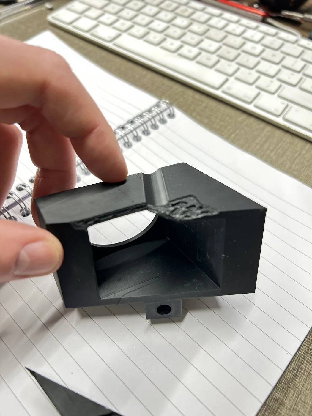 Close-up of the final PET-GF mount held in hand, showing the internal light channel and the bolt-hole mounting tab