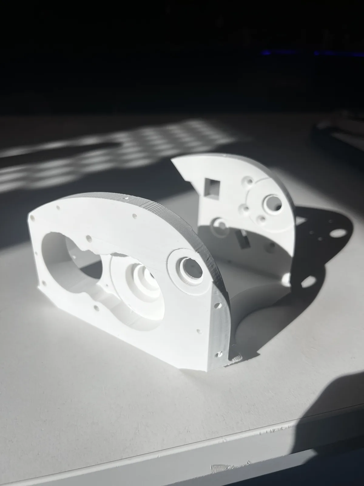 Two curved 3D-printed joint housings for the robotic arm, with bearing seats and mounting holes, printed to tight tolerances
