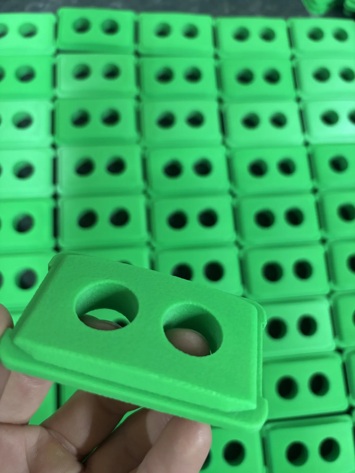 A single green DURABIN lid held up above rows of the finished batch