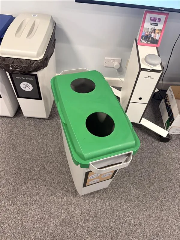 A full size Durable DURABIN recycling bin with a green lid, in an office