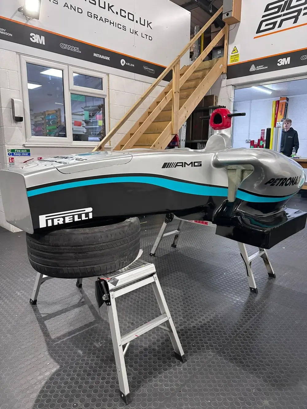 The life size 3D printed F1 car body on stands being vinyl wrapped in race livery