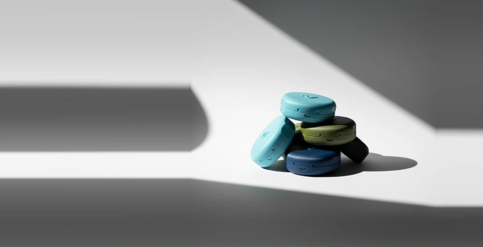 Stack of Pebbl automatic cable organisers in teal, olive, navy and black, 3D printed by 3D Printing Express