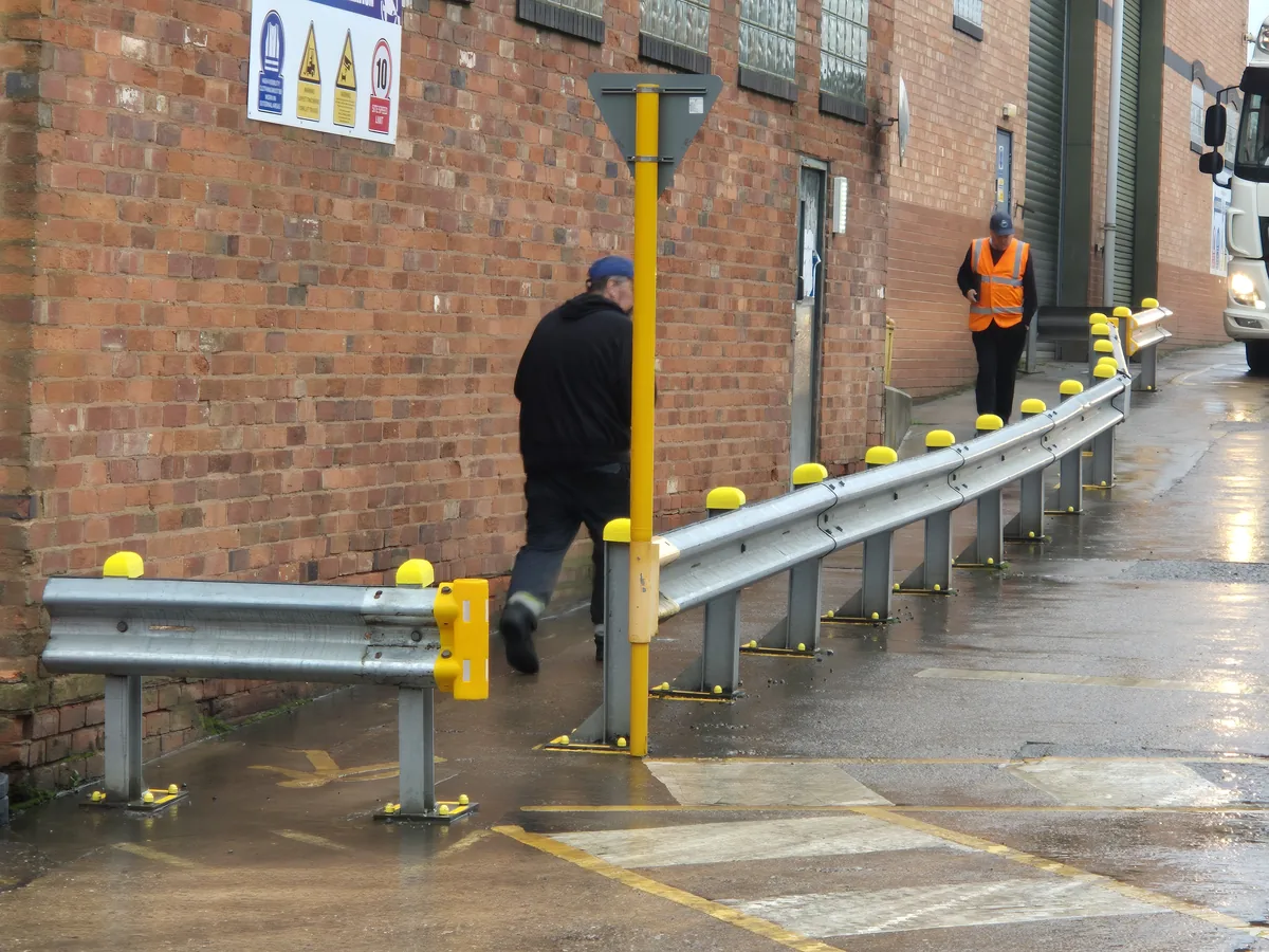 A long run of Armco barrier with yellow 3D-printed Whale Tankers safety caps on every post, fitted along the site walkway