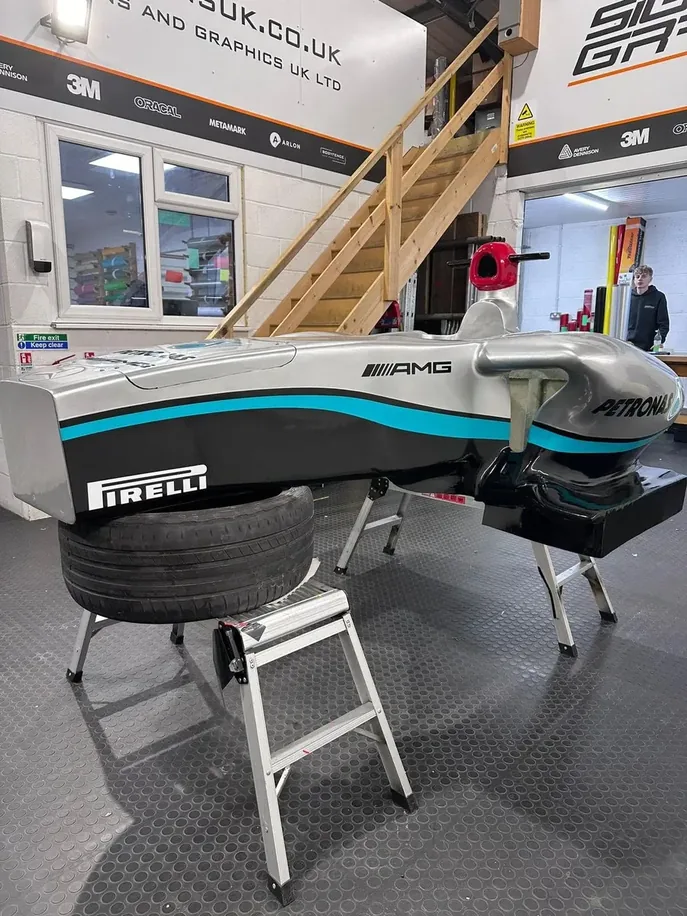 Full-size 3D-printed AMG Petronas F1 display chassis in silver and teal livery, mounted on a Pirelli tyre stand in the 3D Printing Express workshop
