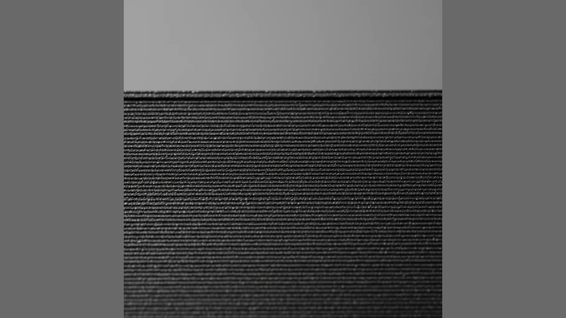 Extreme macro of a deep matte black 3D-printed PA612-ESD surface: uniform fine matte carbon texture