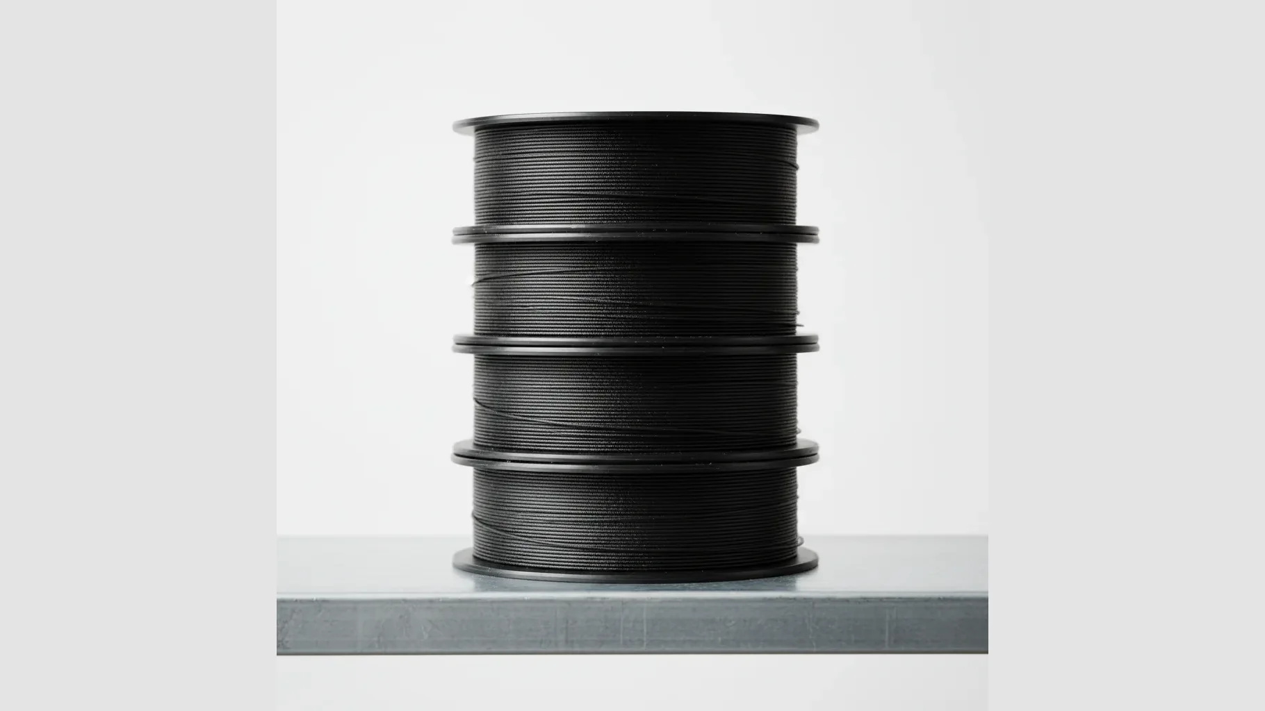 A stack of matte black carbon-fibre ESD nylon filament spools on a shelf