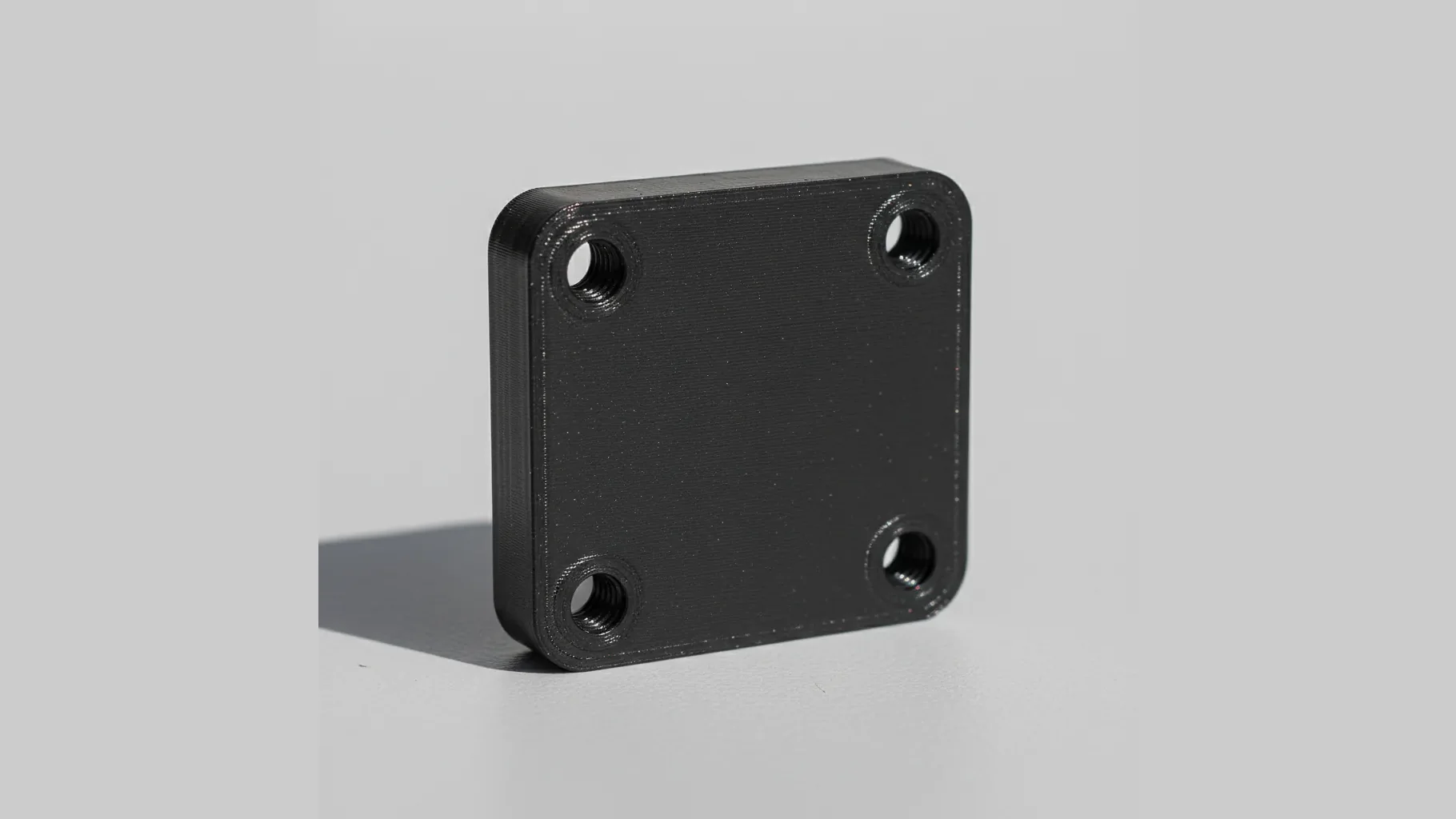 A single matte black 3D-printed PETG-rCF stiff bracket with bolt holes