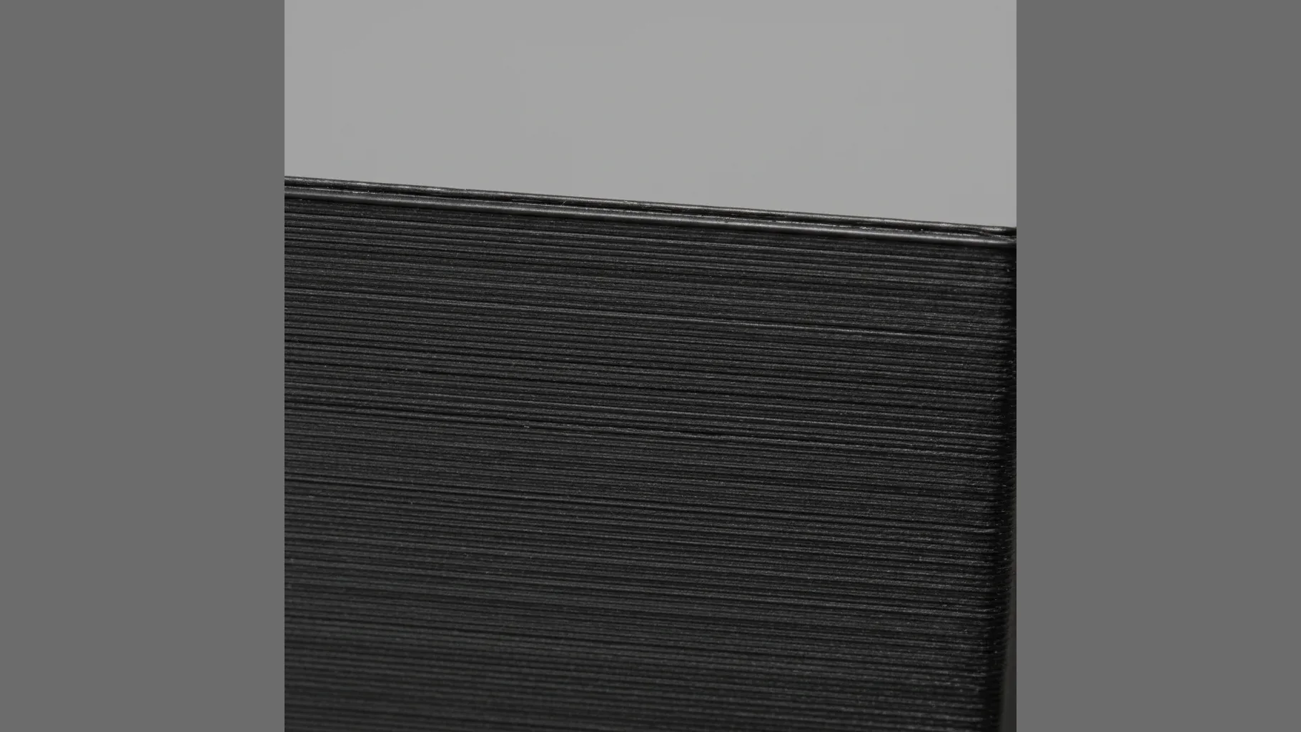 Extreme macro of a matt-black 3D-printed PLA-CF surface: uniform fine matte carbon texture