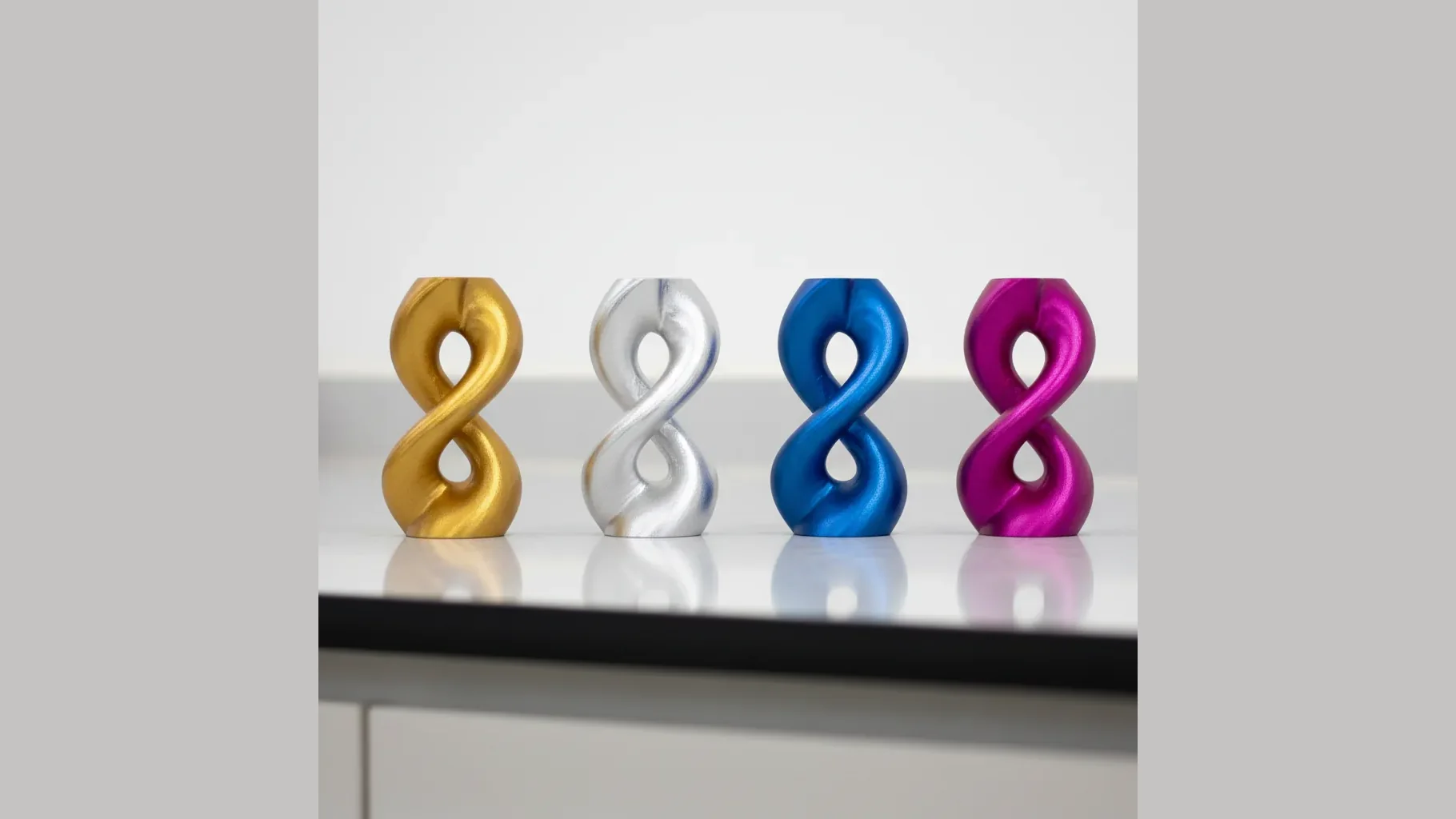 The same small PLA-Silk sculpture 3D-printed in a row of glossy silk colours (gold