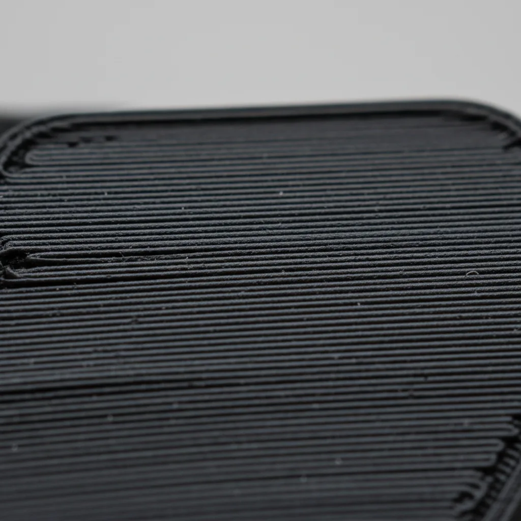Extreme macro of the surface of a matt black flexible 3D-printed TPU part showing fine layer lines and a soft rubbery texture