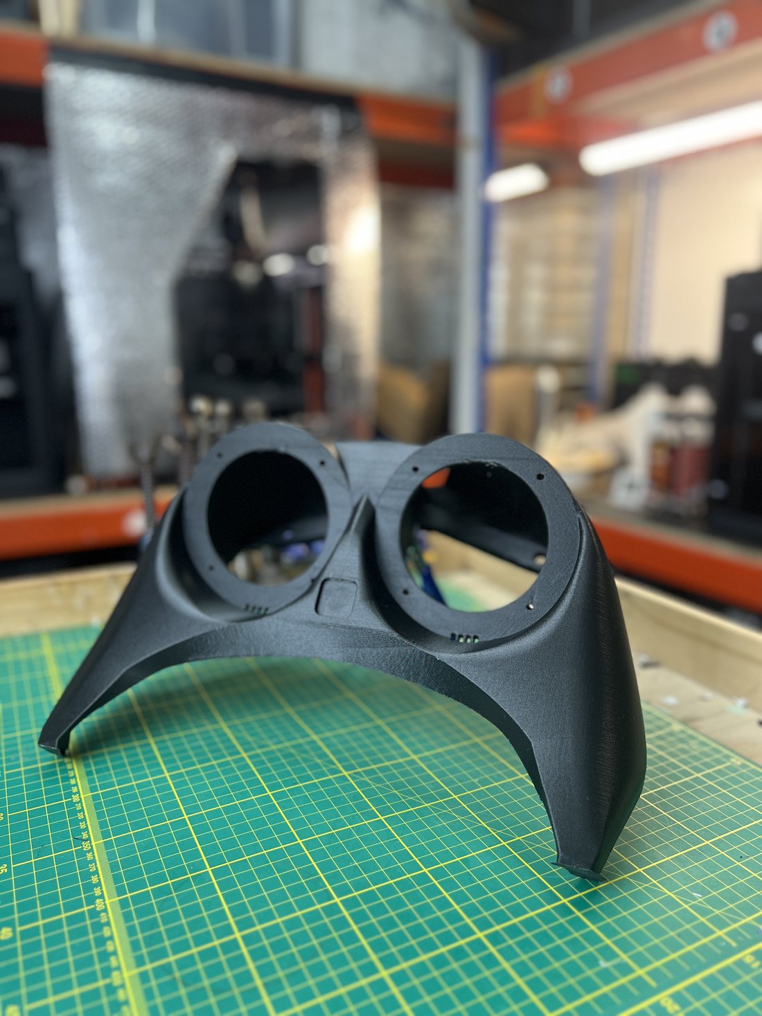 Roberto case study · the 3D-printed twin-gauge jet-ski dashboard console, sanded matte black, on the workshop cutting mat — our printed part as the subject