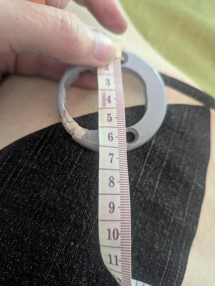 A hand holding a cracked grey Fiamma Caravanstore awning end piece against a tape measure