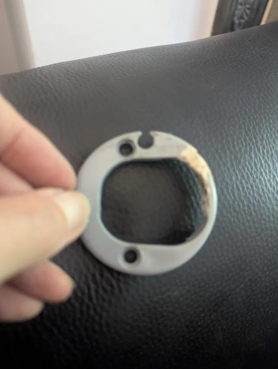 A grey Fiamma awning end piece held up by hand, showing the chip and crack in the original ring