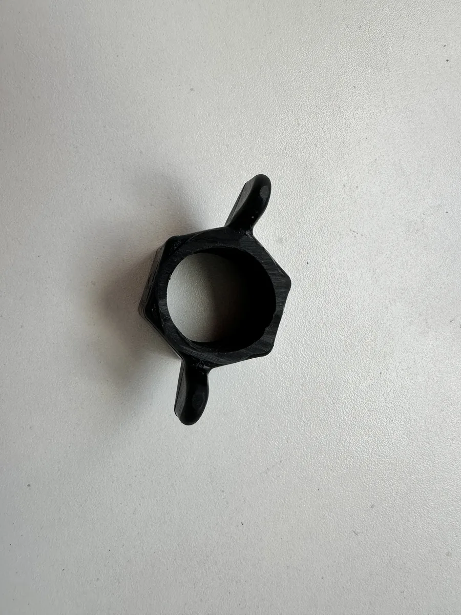 A black wing nut reference part with two wing tabs and a hex body around a round threaded bore